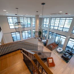 a lobby with tables, chairs and stairs